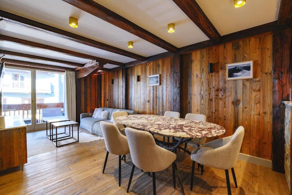 een woonkamer met een tafel, stoelen en een bank bij Luxury suite 70m2 balcon courchevel1850 parking in Courchevel