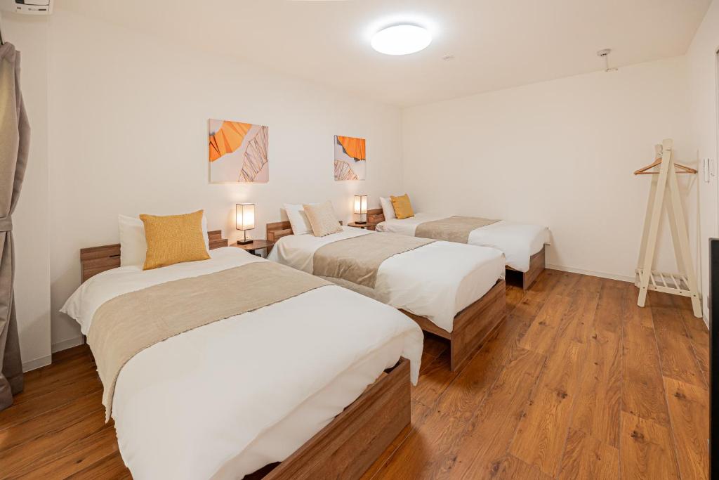 Habitación con 3 camas y una cruz en la pared. en U Stay 西川口, en Kawaguchi