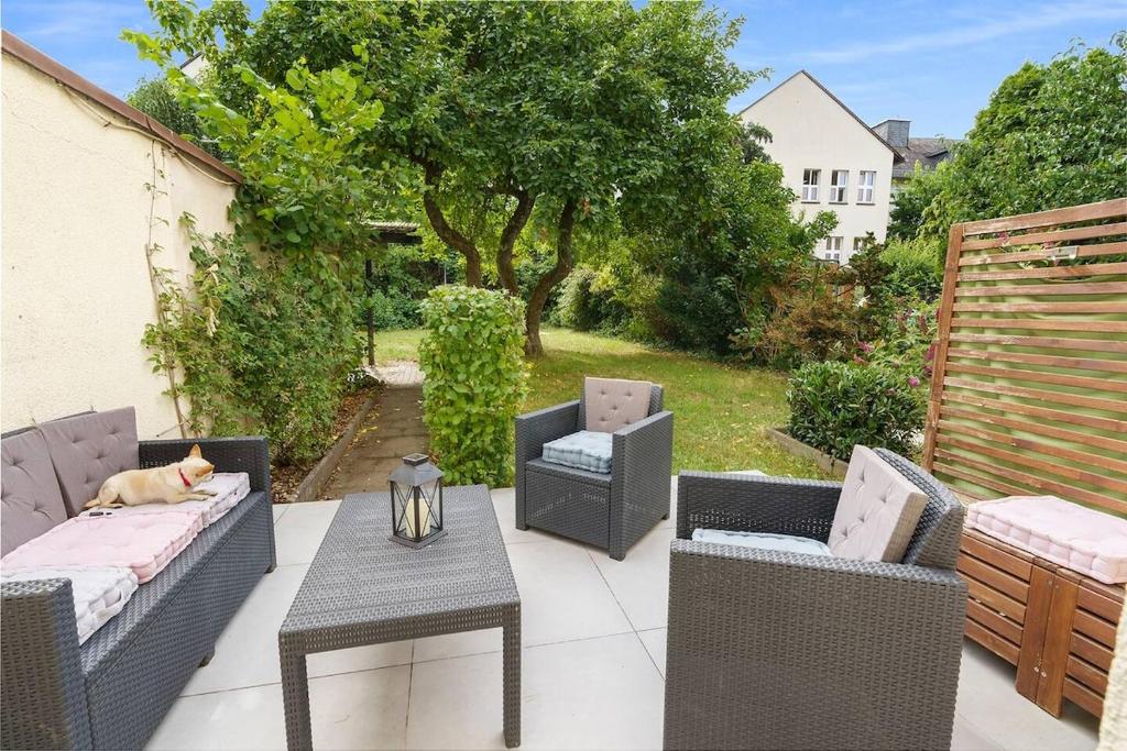a patio with chairs and a dog laying on a table at Moderne Traumwohnung mit Traumgarten in Mayen