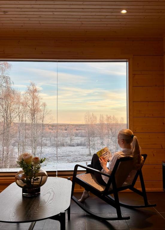 a man and woman sitting in a chair in front of a window at Kajo Sky Lodge in Rovaniemi