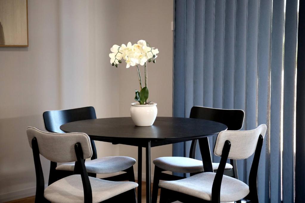 a black table with chairs and a vase with white flowers at Broome Villa Oasis in Broome