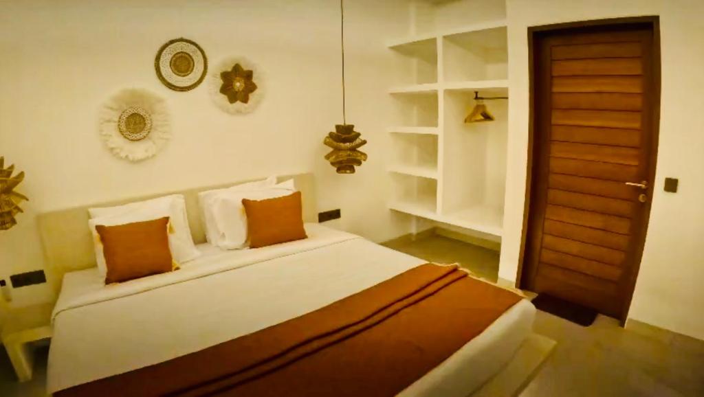 Villa JAYA Nyanyi في Munggu: غرفة نوم بسرير وملاءات بيضاء ومخدات برتقالية