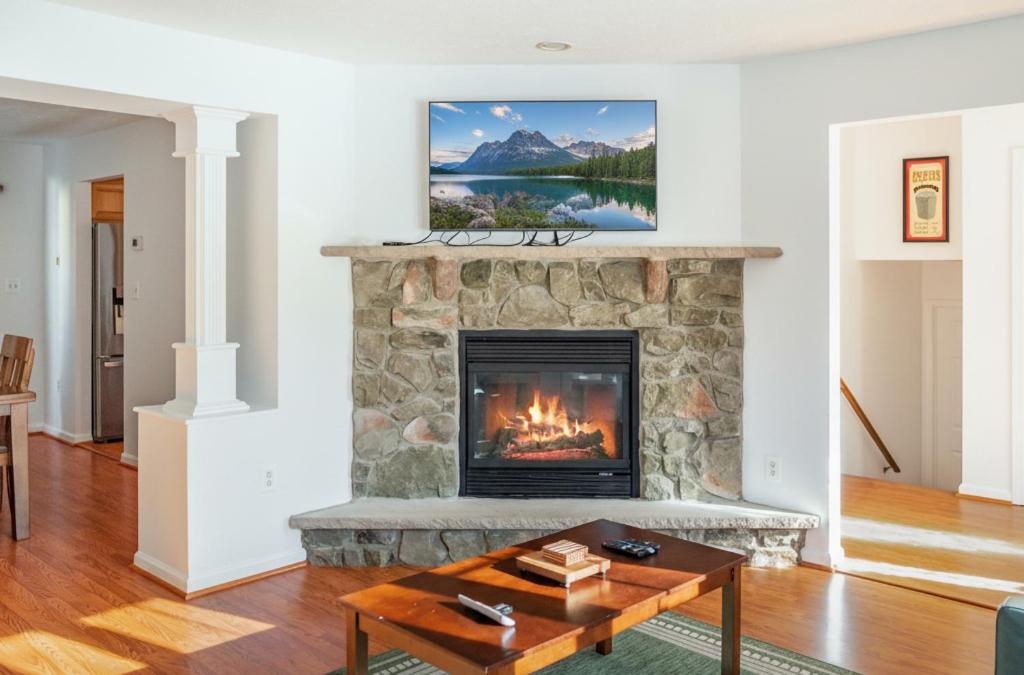 a living room with a stone fireplace with a picture at Spacious 3BR House, Hot Tub, Firepit, Ski Access! in Emerald Lakes