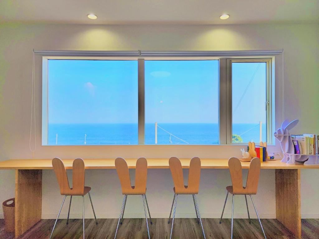 a table with four chairs in front of a large window at 「淡路島一棟貸宿　野うさぎ 」高台から海を望む貸別荘！2023年新築離れの素泊まり in Noda