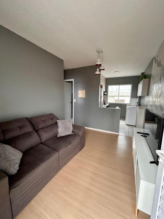 a living room with a brown couch and a kitchen at Apartment COP30 in Ananindeua