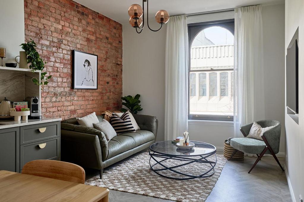 a living room with a couch and a brick wall at The Avenue in Launceston