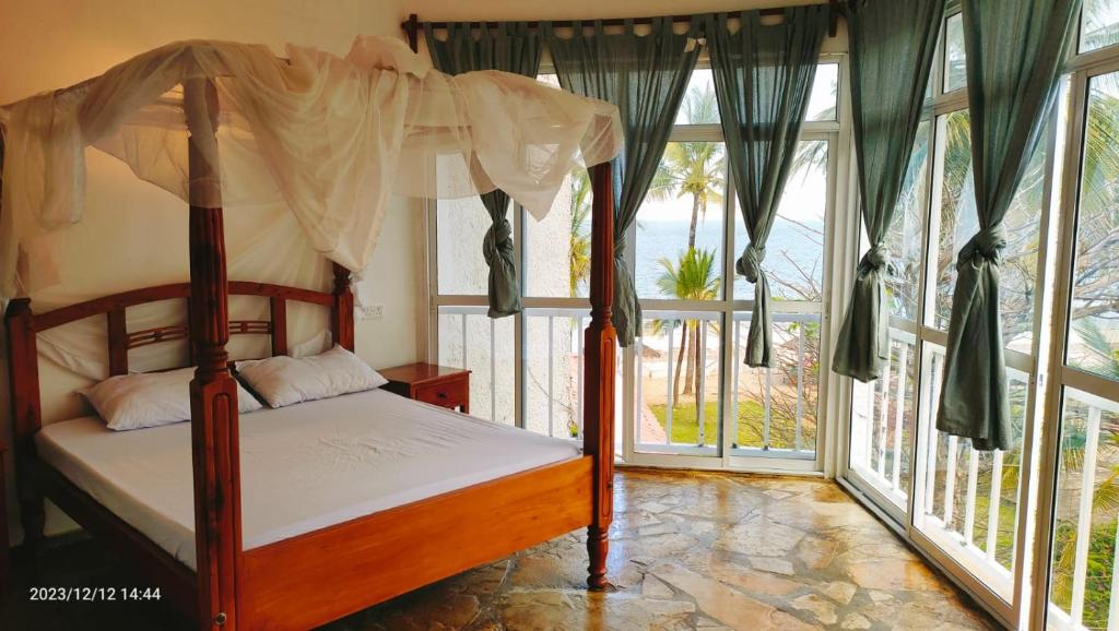 a bedroom with a canopy bed in a room with windows at Guestroom in Malindi