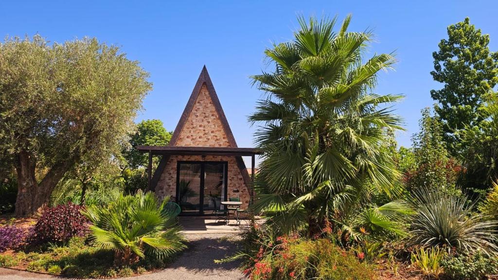 een prieel in een tuin met een palmboom bij l'oasis de paix refugee unique à Marrakech in Aït Amara