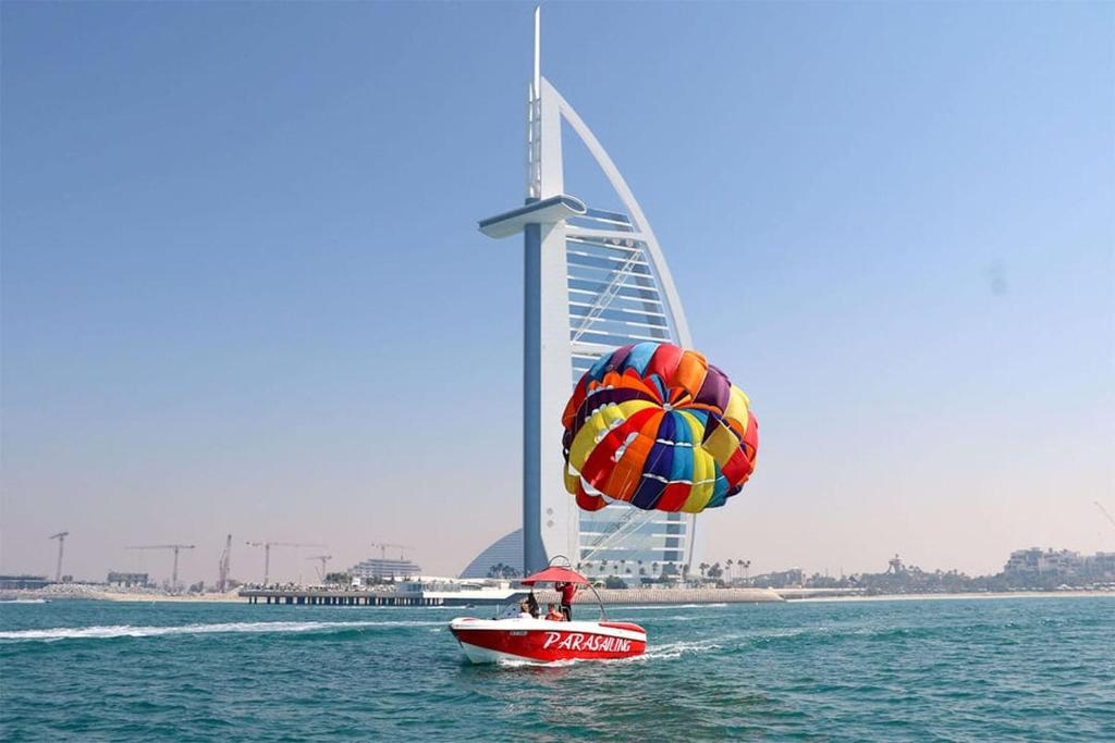 迪拜Parasailing Boat Dubai的船上有降落伞的人在水中