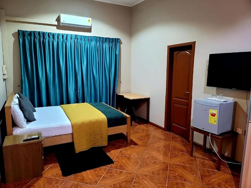 ein Schlafzimmer mit einem Bett mit einem blauen Vorhang und einem TV in der Unterkunft Ghouse room D Ideal For Friends family And Corporate in Lateman