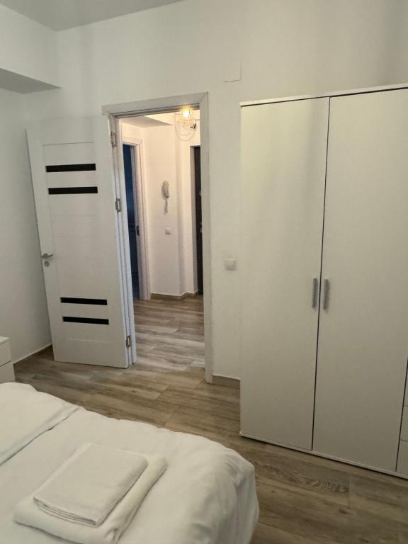 a white bedroom with a bed and a closet at illy apartament in Craiova