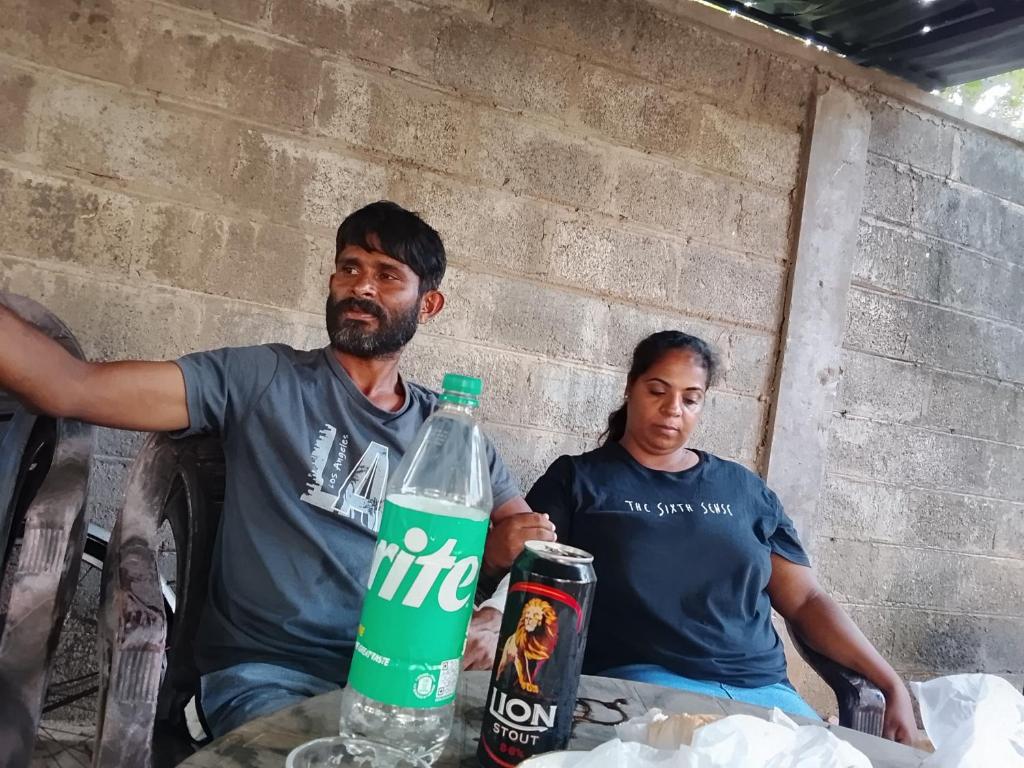 two men sitting next to a table with a bottle of water at Wandana Holiday Home in Anuradhapura