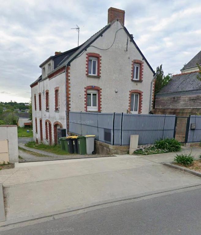 an old house with a fence in front of it at Comme chez soi in Châteaubriant