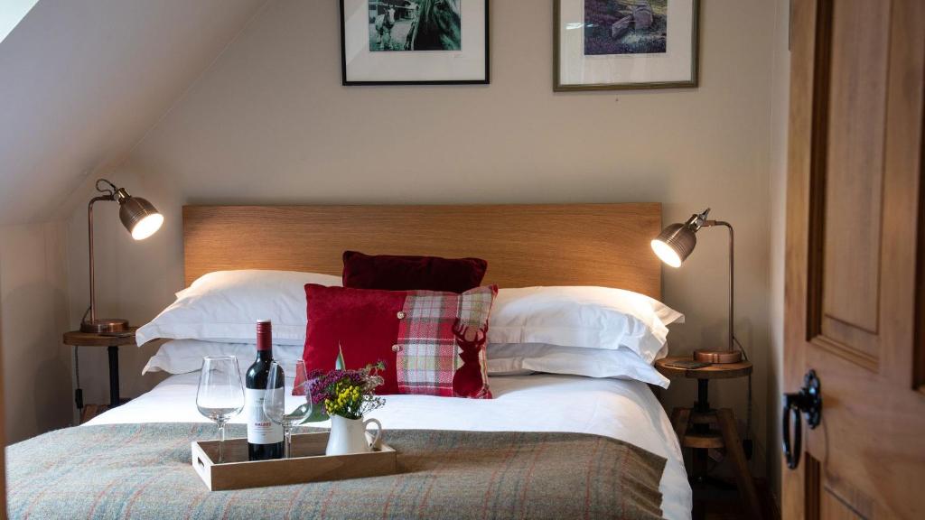 a bedroom with a bed with two bottles of wine and two glasses at Tanar View in Aboyne