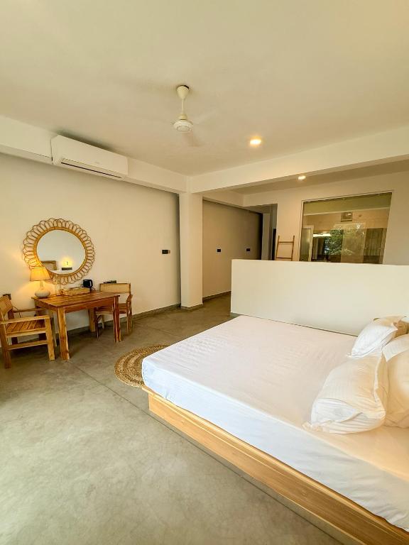 a bedroom with a large bed and a table at OLA Tangalle in Tangalle