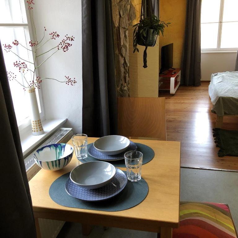 ein Holztisch mit zwei Tellern und Gläsern darauf in der Unterkunft Grand Central- Studio Apartment in Krummennaab