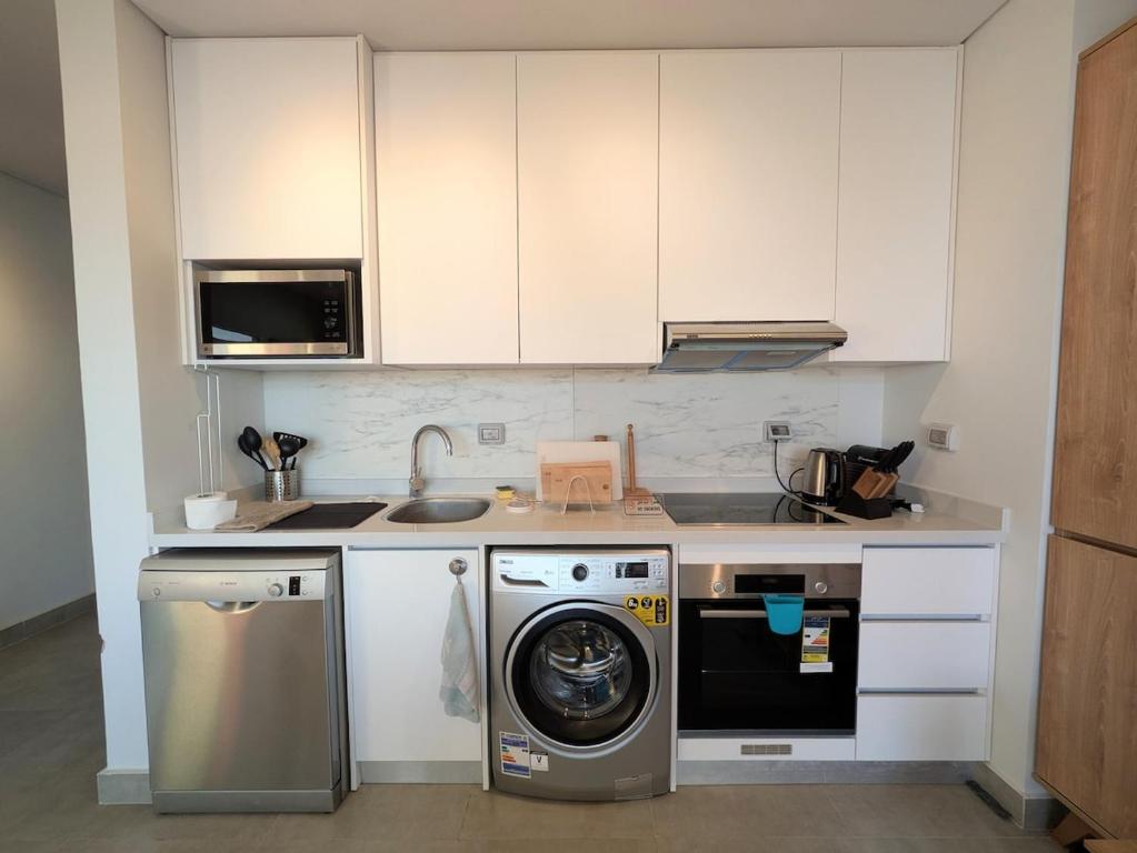 a kitchen with a washing machine and a microwave at Panoramic Seaview Somabay 1BR Apartment in Mesca in Hurghada