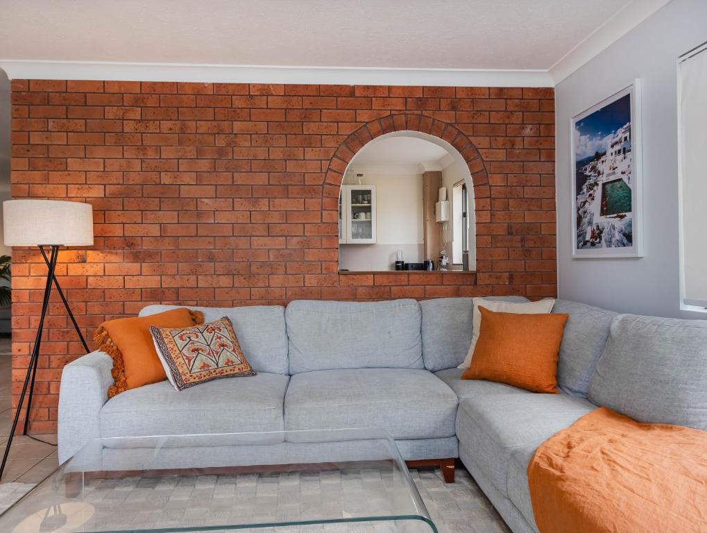 a living room with a couch and a brick wall at Layback on Marine in Kingscliff
