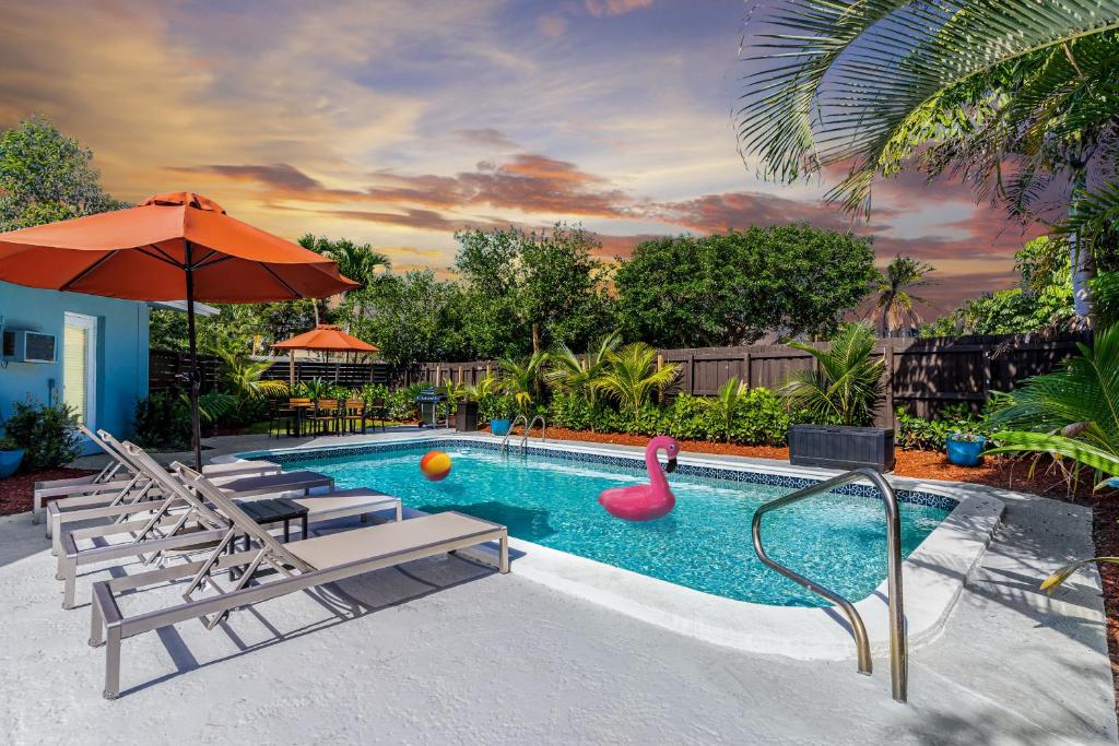 ein Swimmingpool mit einem rosa Schwan, Stühlen und einem Sonnenschirm in der Unterkunft Ventur Tropical with Elite Pool & Ultimate Fun Zone in Fort Lauderdale