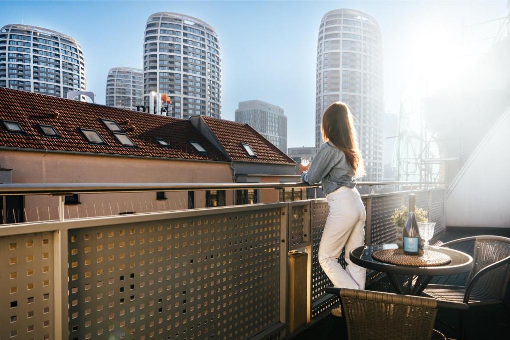 a woman standing on a balcony looking at the city at Business & Family Ambiente Apartments in Bratislava