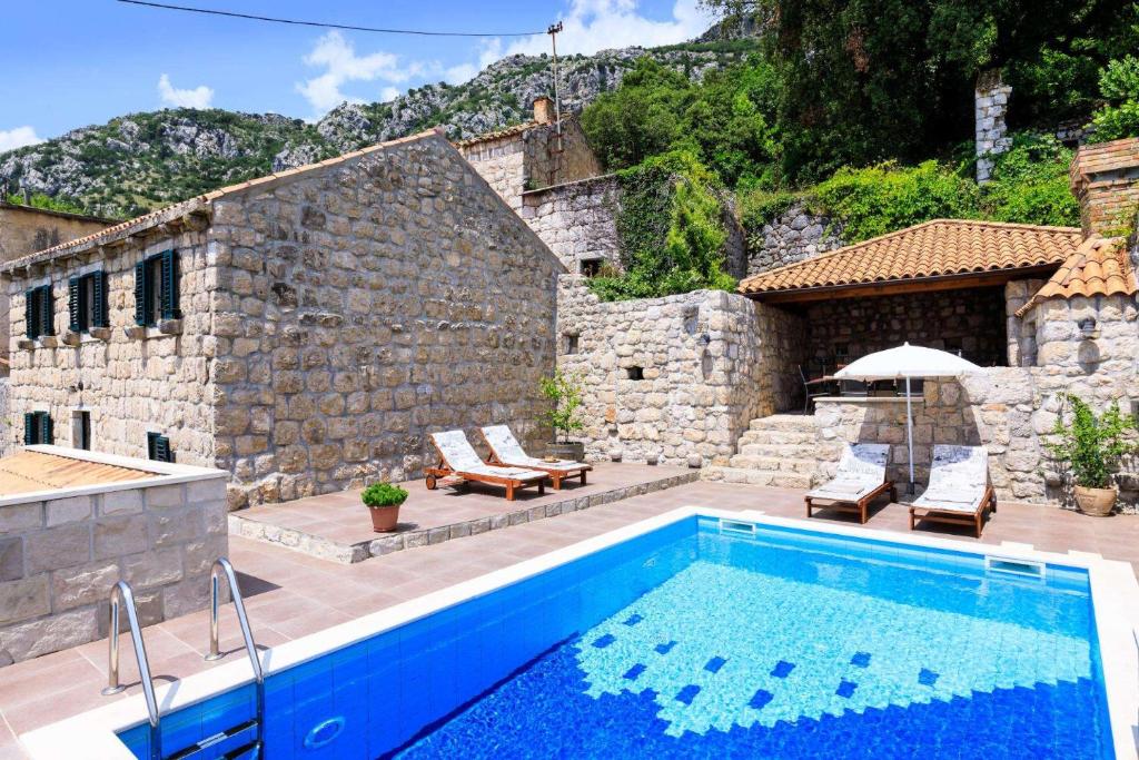 a swimming pool in front of a stone building at Luciana by Vintage Travel in Mihanići