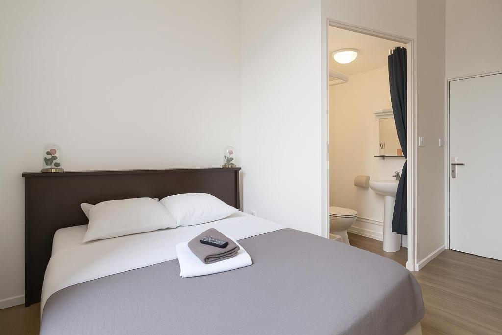 a bedroom with a large bed with a book on it at Hôtel Le Paris Brest in Lens