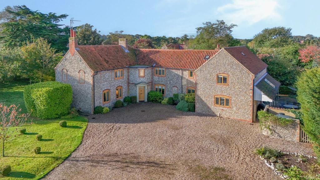 an aerial view of a large stone house with a driveway at Orchard House 140 in Blakeney