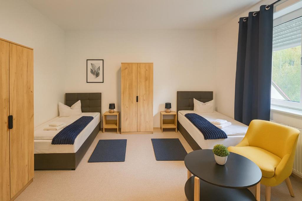 una habitación de hotel con dos camas y una silla en SUNNYHOME Monteurwohnungen und Apartments in Bodenwöhr, en Bodenwöhr