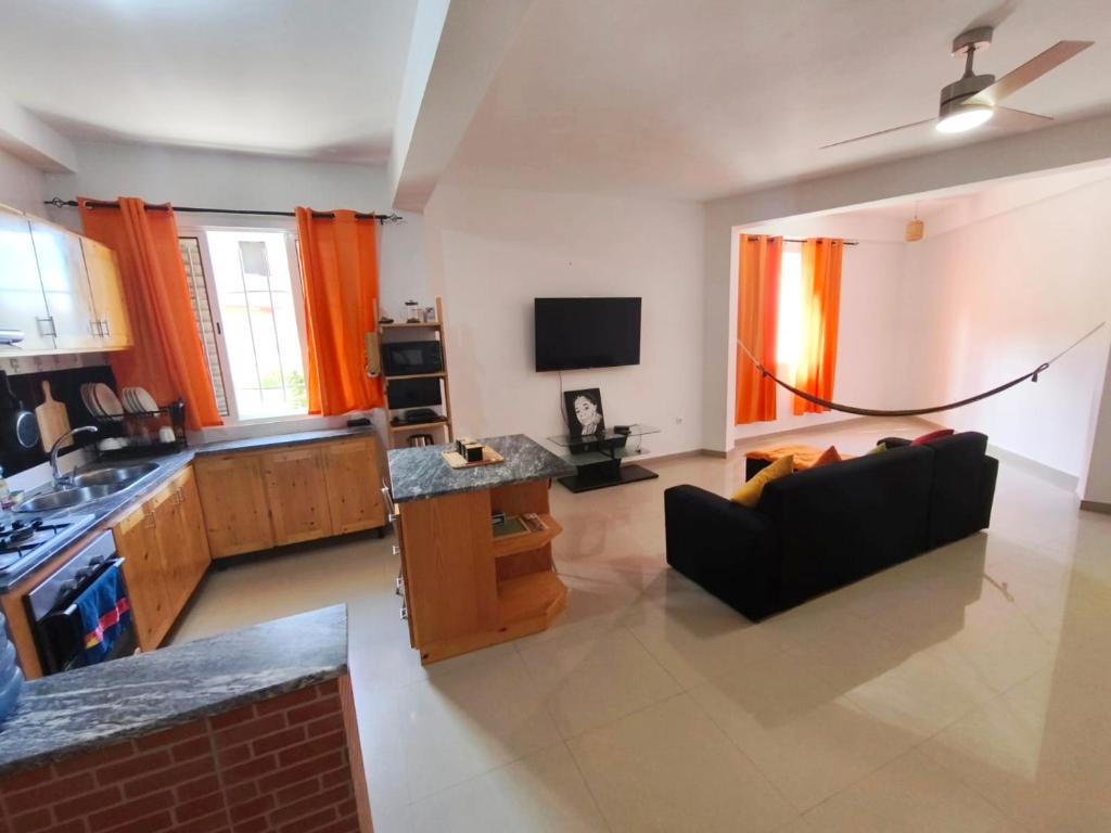 a kitchen and living room with a couch and a tv at Casa Colibri - Confort et Authentique, à 300m de la plage ! in Mindelo