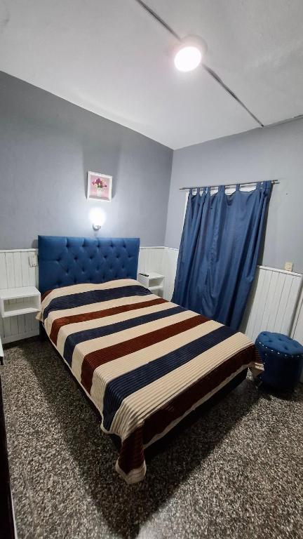 una camera da letto con un letto grande con testiera blu di Hospedaje Artigas a Corrientes