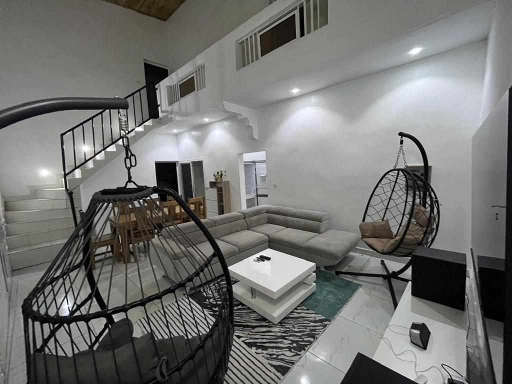 una sala de estar con un sofá y dos jaulas colgantes en Keur joie, en Mbour