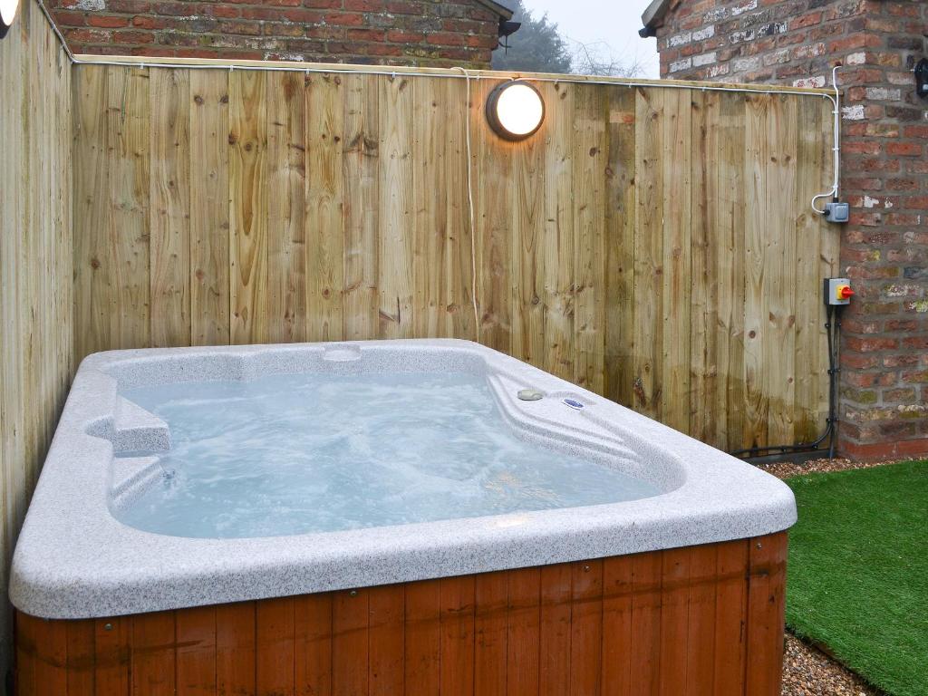 a hot tub in a yard next to a wooden fence at The Old Forge in Burshill