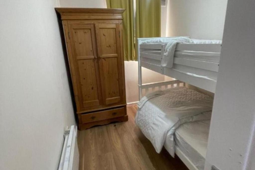 a bedroom with bunk beds and a wooden cabinet at Hillside Retreat in Wolverhampton in Wolverhampton