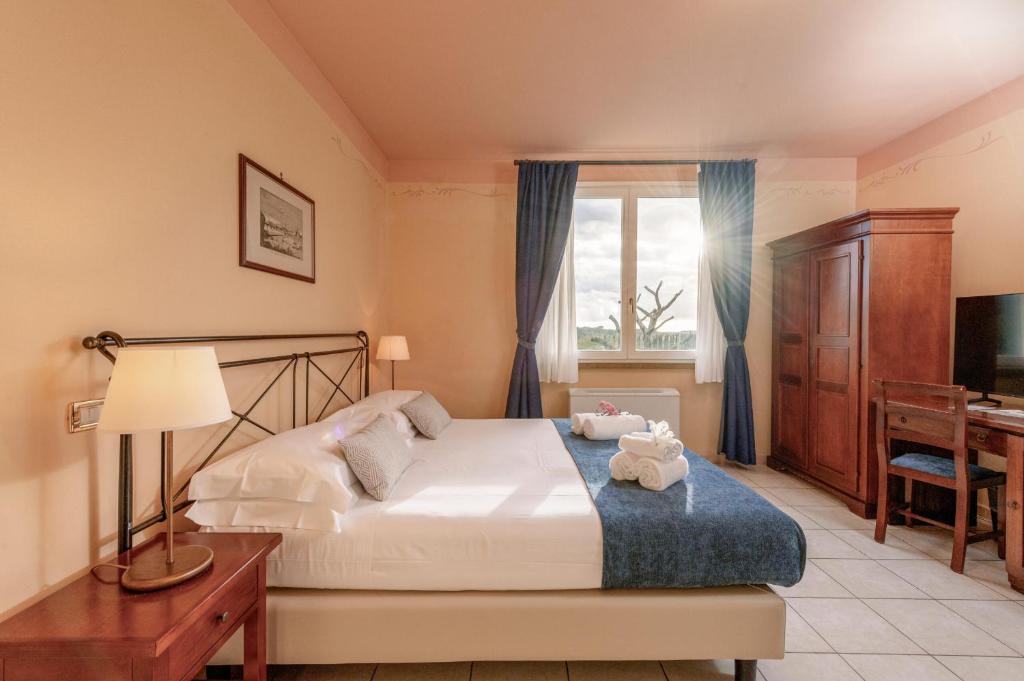 a bedroom with a bed with a desk and a television at Hotiday Toscana Riparbella in Riparbella