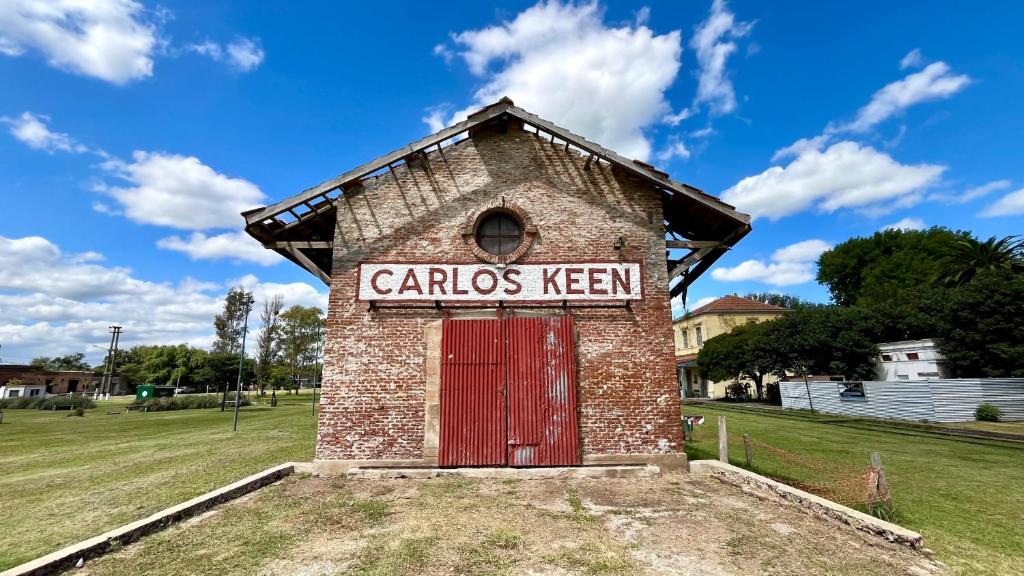 a small brick building with a red door at Encanto Rural Keen in Luján