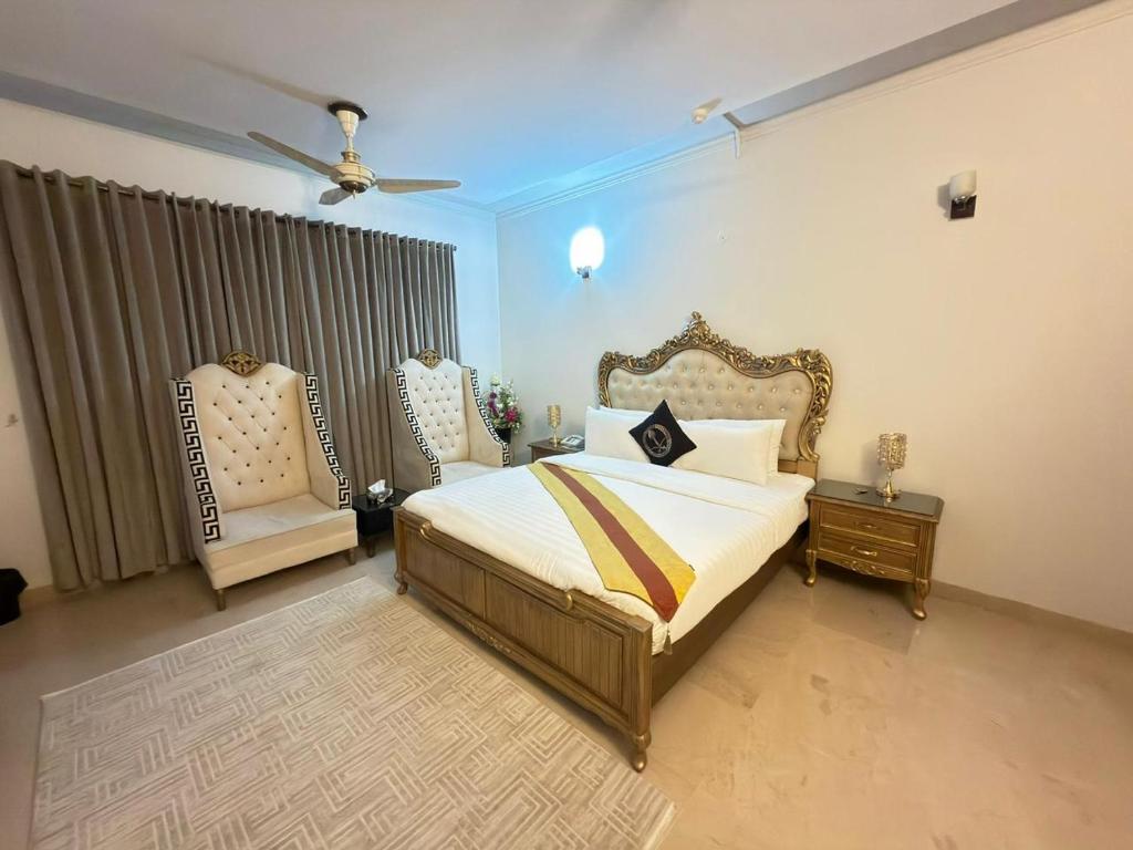 a bedroom with a bed and two chairs at MELBERRY Guest House in Islamabad
