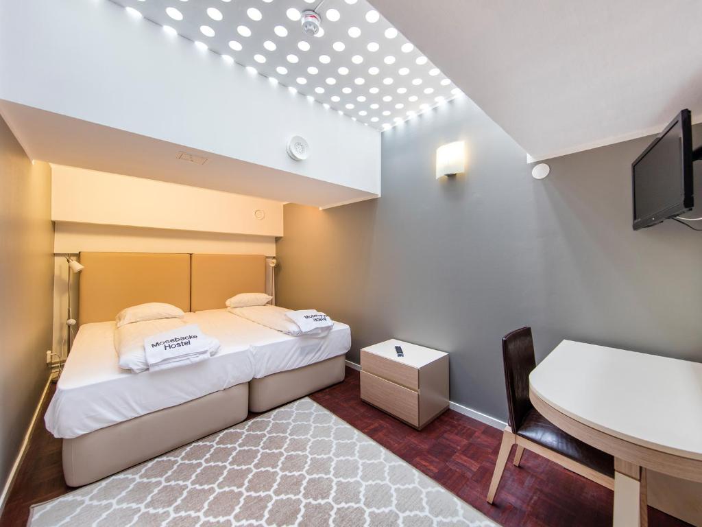 Kleines Zimmer mit einem Bett, einem Schreibtisch und einem Waschbecken in der Unterkunft Mosebacke Hostel in Stockholm