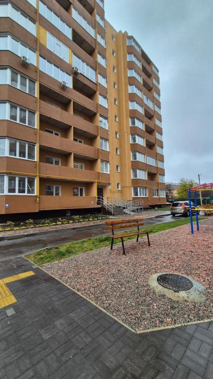 una panchina seduta di fronte a un grande edificio di Затишна квартира в центрі! a Černihiv