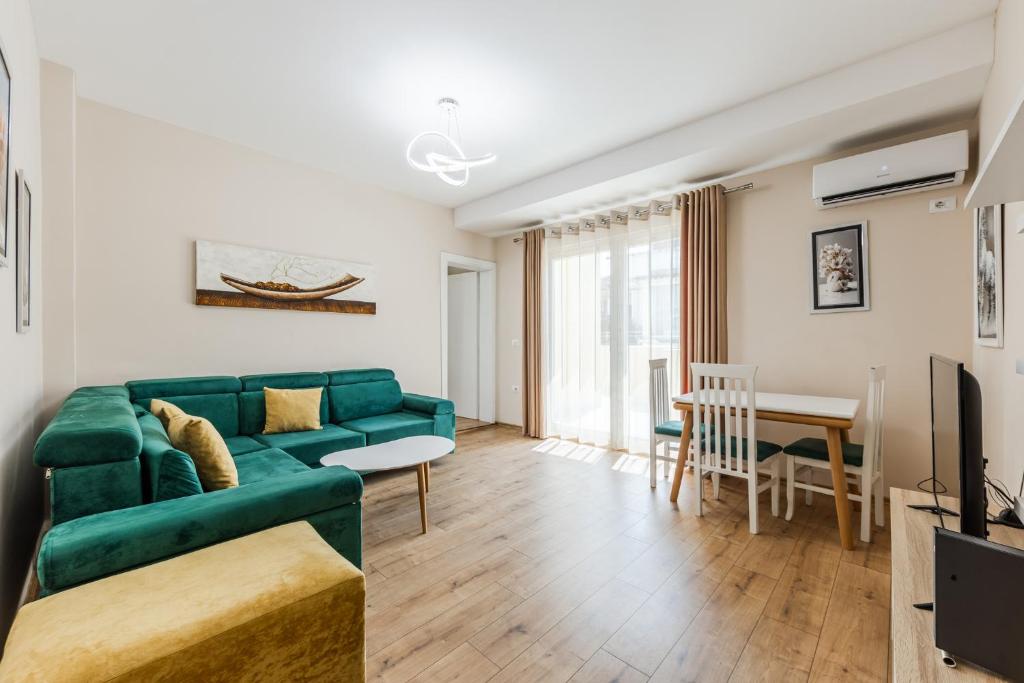 a living room with a green couch and a table at Luma Penthouses by Kondo Stays in Tirana