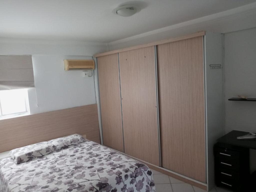 a bedroom with a bed and a large wooden cabinet at Apartamento in Cabedelo