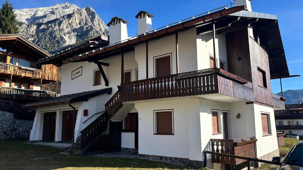 ein weißes Gebäude mit einem Balkon und einem Berg in der Unterkunft Ca' Letizia in San Vito di Cadore