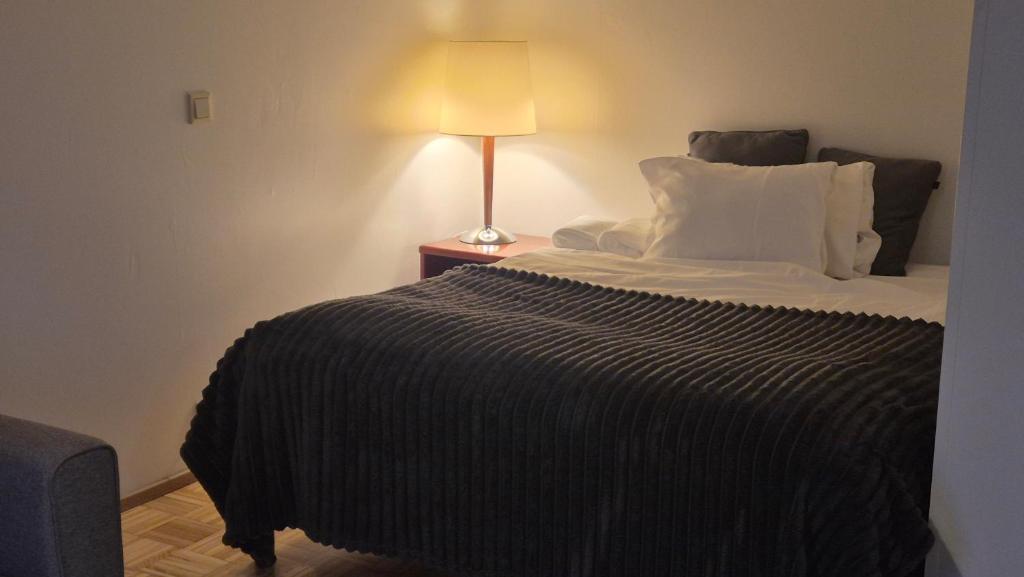 a bed with a black blanket and a lamp on a table at Studio at Tottinkatu in Savonlinna