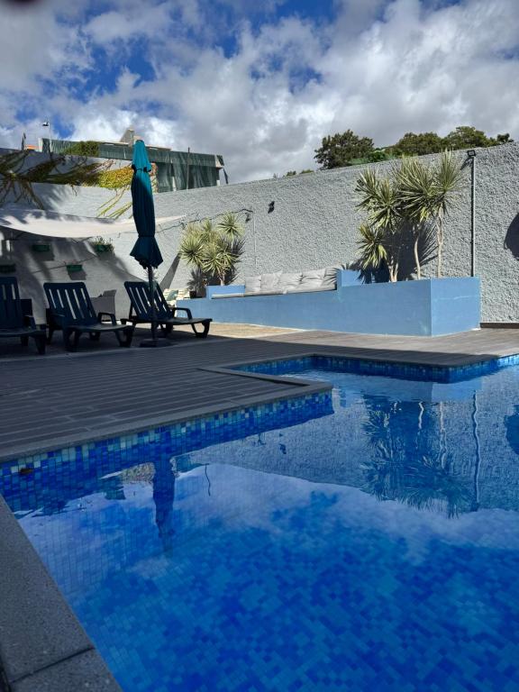 een zwembad met twee stoelen en een parasol ernaast bij Monte Verde in Funchal