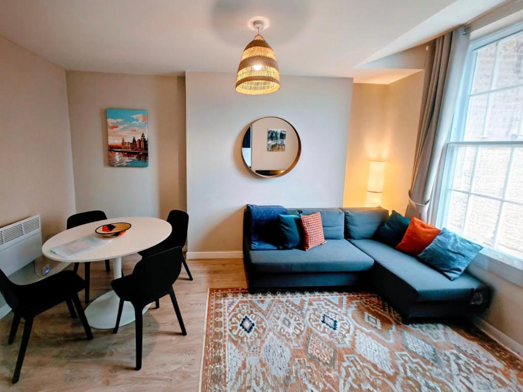 een woonkamer met een blauwe bank en een tafel bij Victoria's Bright Georgian Apartment in Liverpool