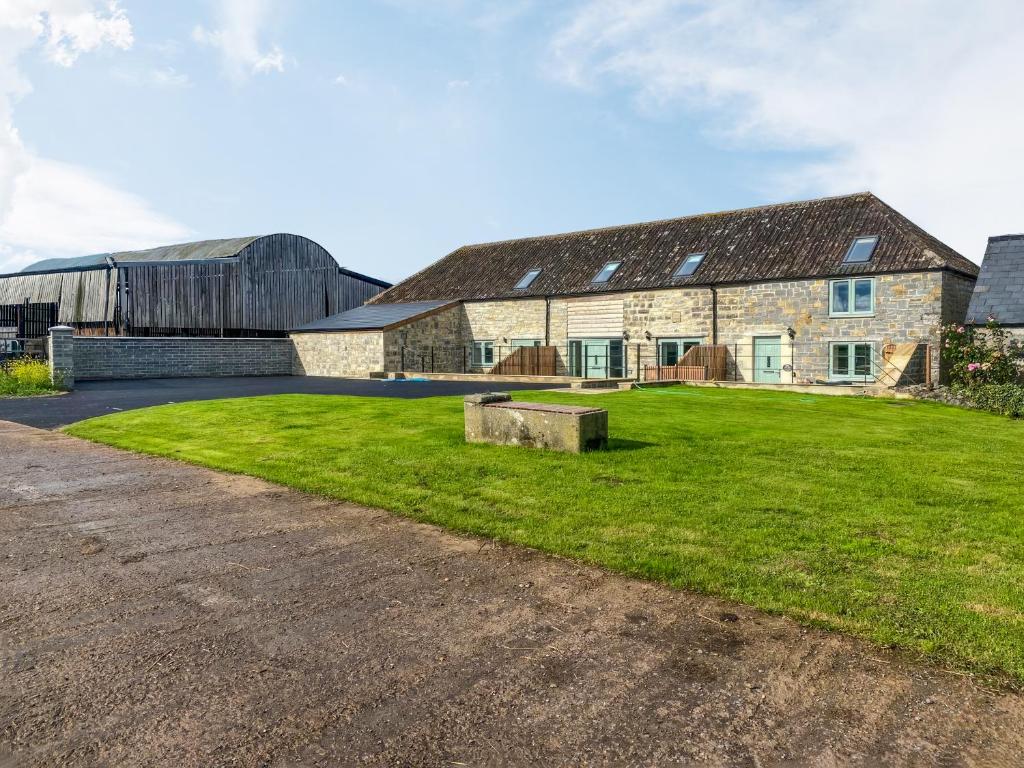 an old stone barn with a grassy field in front of it at The Mill House Uk47418 in Curry Mallet