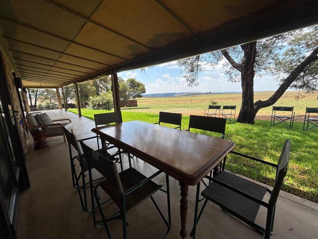 a table and chairs on a porch with a view of a field at Sibani Lodge - Glamping Tents in Krugersdorp