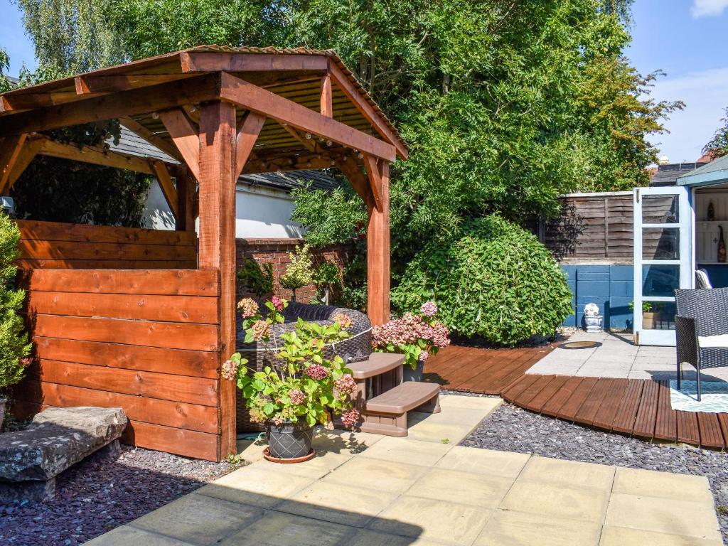 a wooden gazebo with flowers in a yard at Beval Cottage in Abergavenny