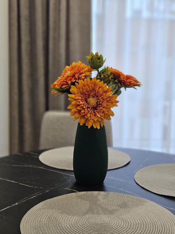 a green vase with orange flowers on a table at ZEN home in Chişinău