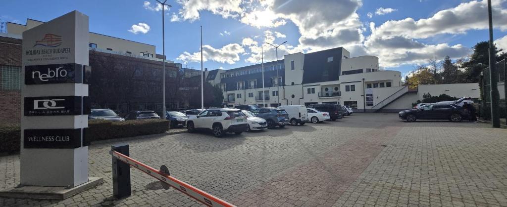 ブダペストにあるHoliday Beach Budapest Hotelの建物の前に車が駐車されている駐車場