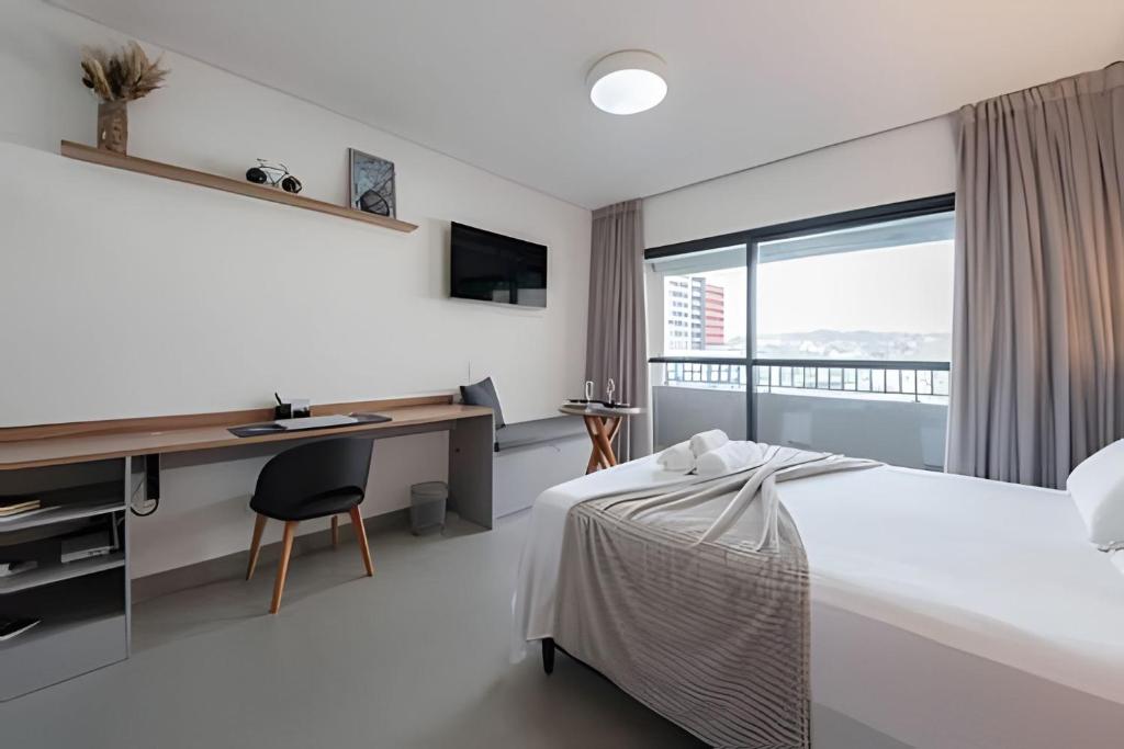 a bedroom with a bed and a desk and a window at Studio Elegante Próxi a USP By Marcolini in Sao Paulo